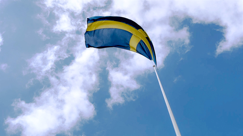 Svenska flaggan hissad med en blå himmel i bakgrunden.