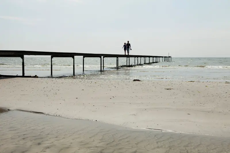 Bingsmarken strand, två personer gåendes på brygga