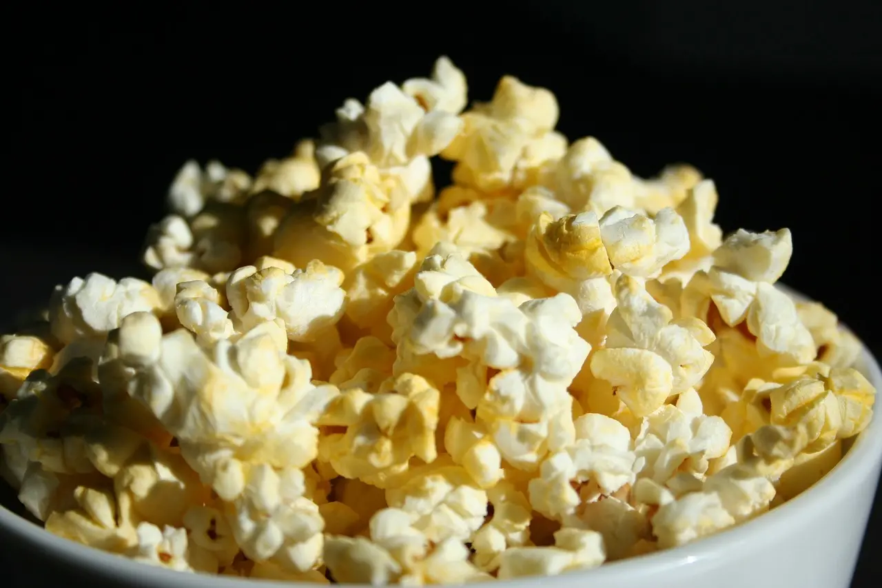 En vit skål med popcorn.