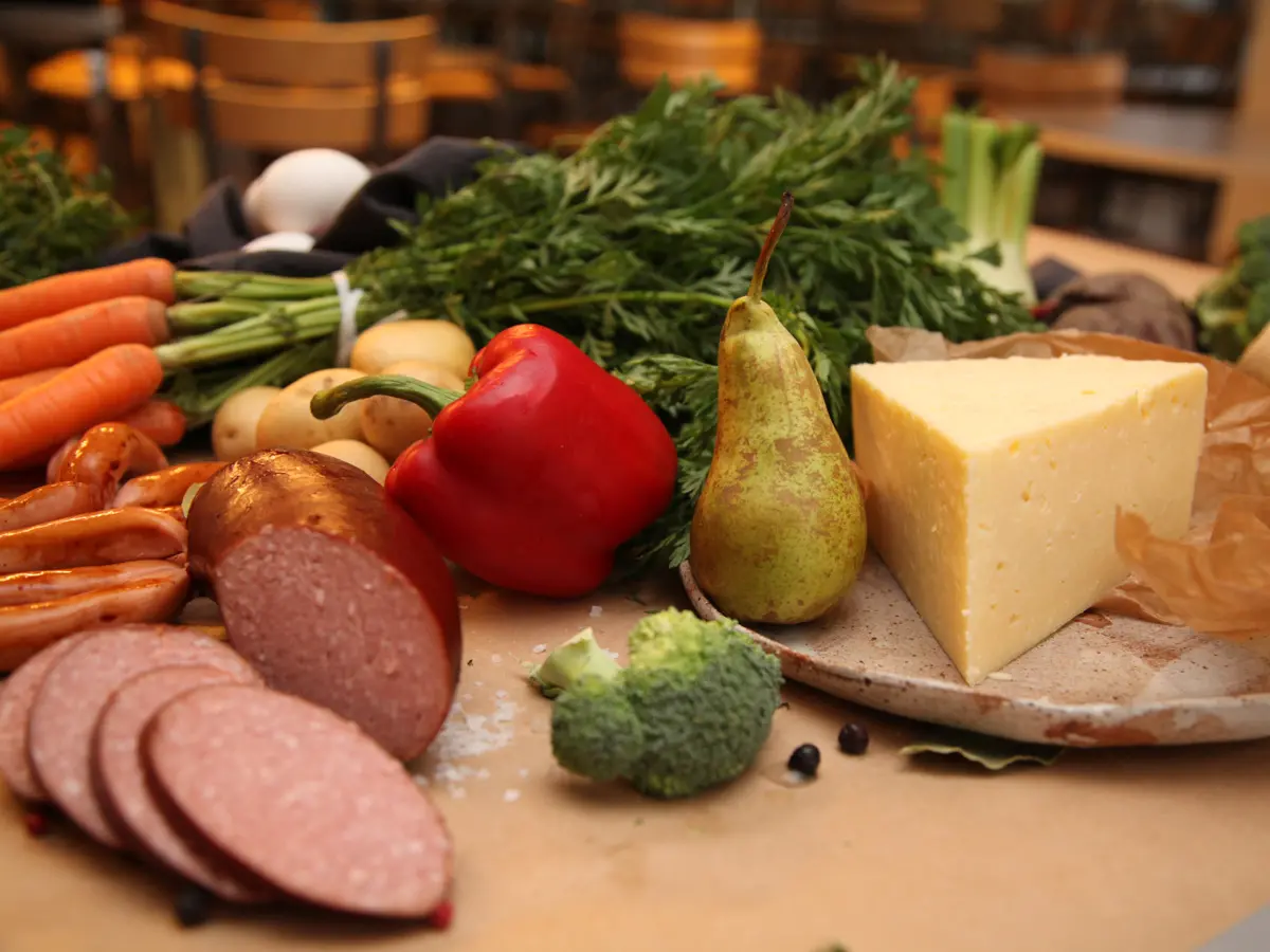 Mat uppdukat på bord med korv, grönsaker, ost och frukt.